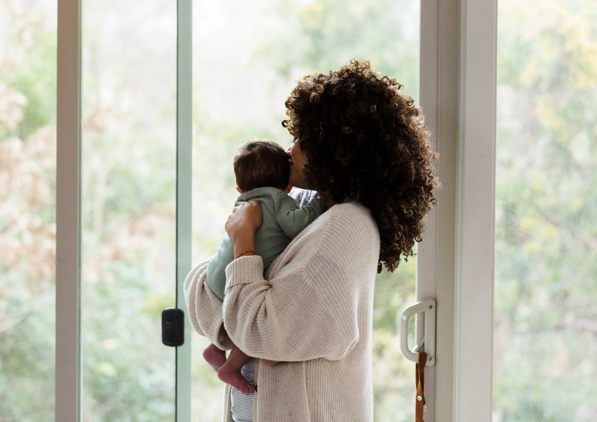 New mother holding her baby by a window